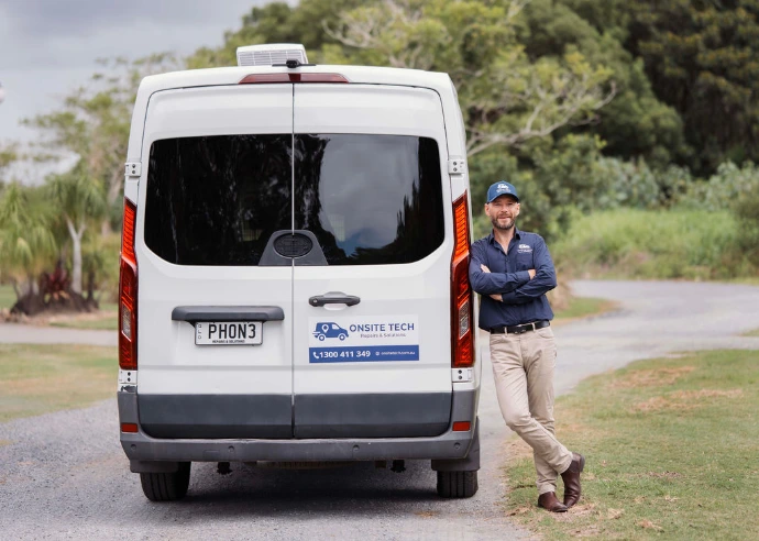 Business owner standing next to branded Onsite Tech mobile repair van